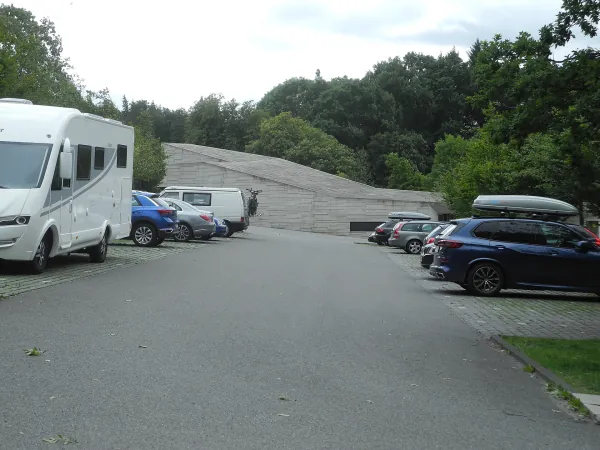 Der Besucherparkplatz am Herkules mit parkenden Autos und Wohnmobilen vor dem Besucherzentrum.